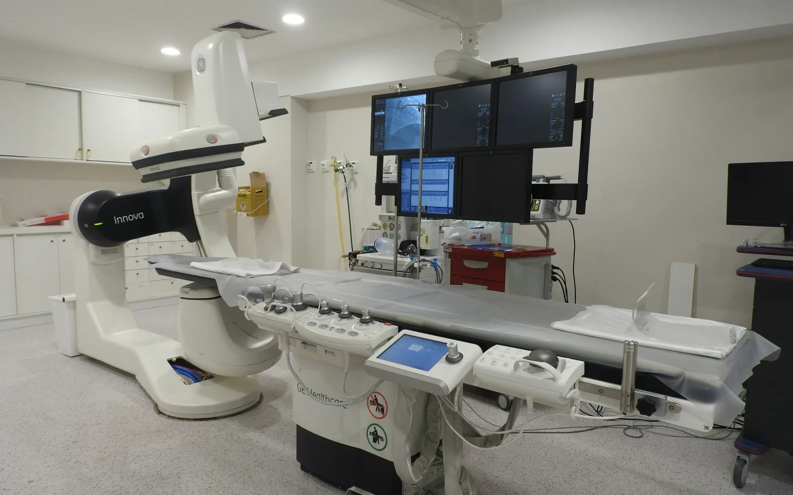 Interventional radiology suite with an angiography C-arm and monitors