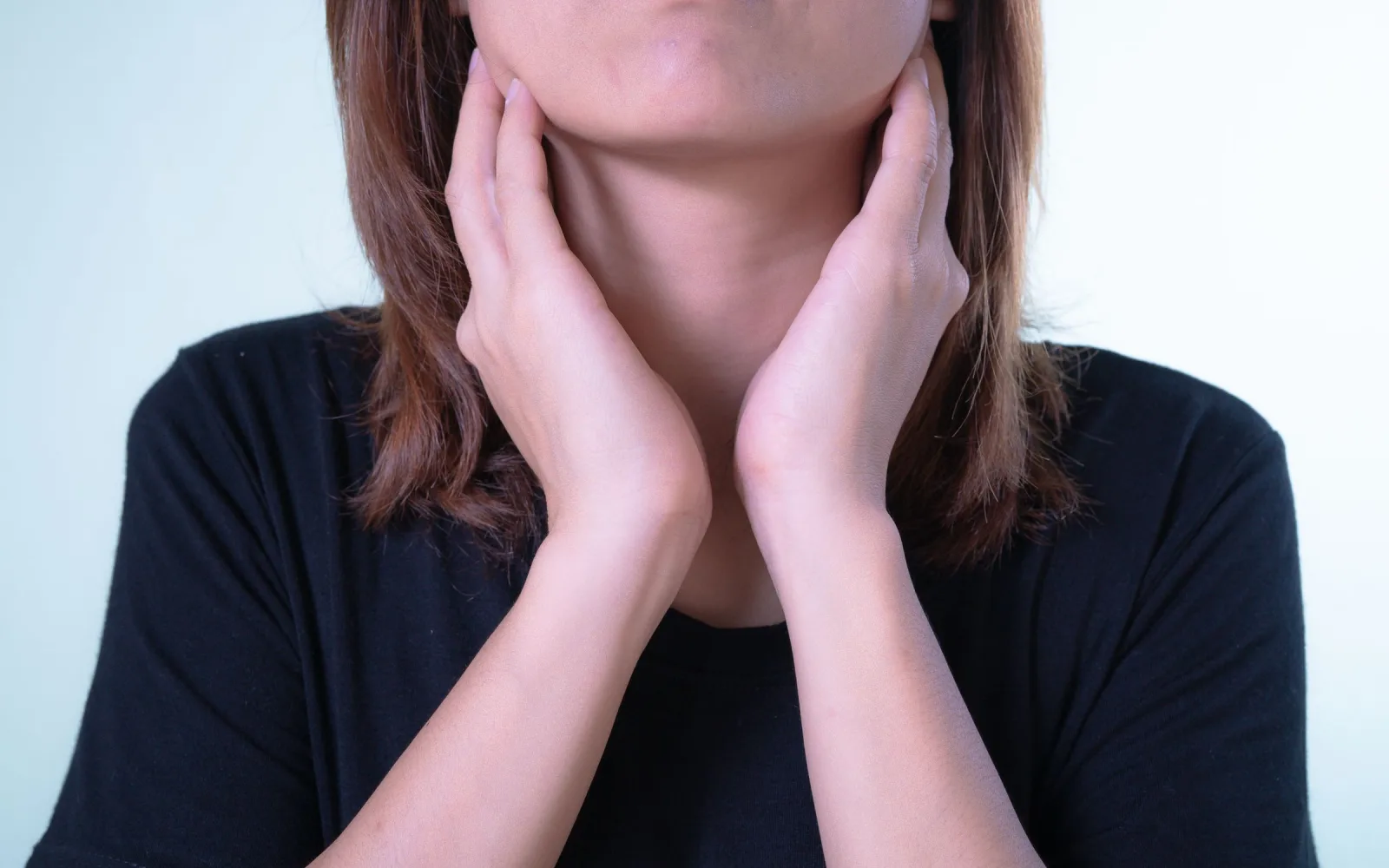 Woman touching the front of her neck where the thyroid sits
